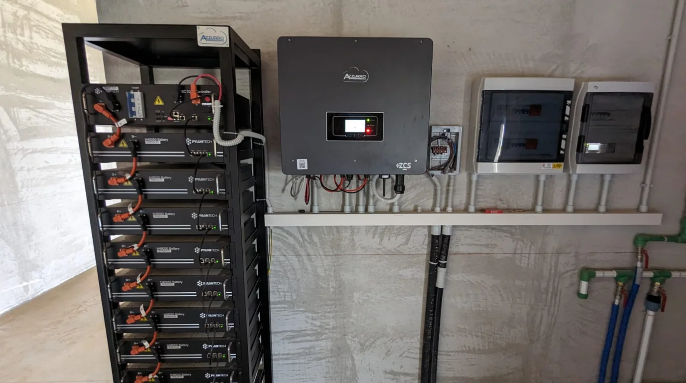 Estratto fotografico di un sistema di accumulo a batterie: armadio con moduli impilati e cablaggi, affiancato dall’inverter e dal monitoraggio, montati a parete